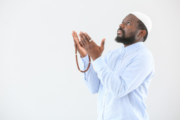 Wall Mural - African-American Muslim man praying against light background