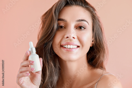 Fotomural Beautiful young woman with bottle of serum on color background
