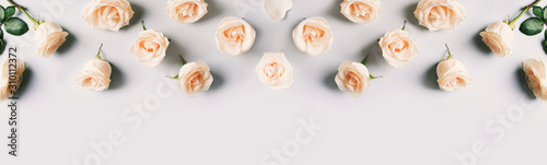 Fotomural White roses frame flat lay on blue background.