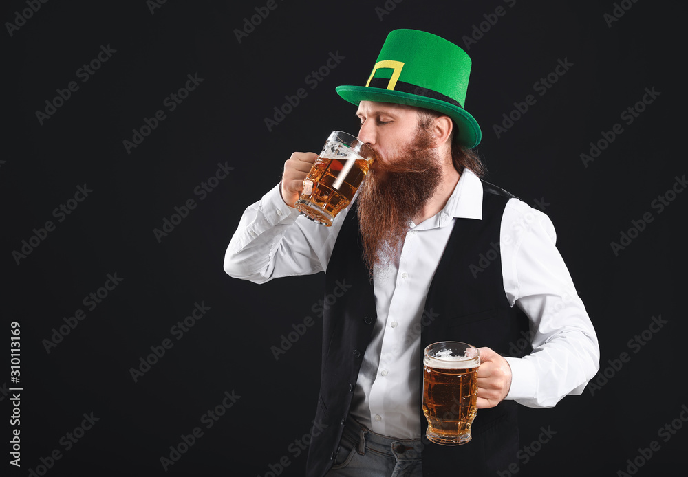 Bearded man with glasses of beer on dark background. St. Patrick's Day celebration