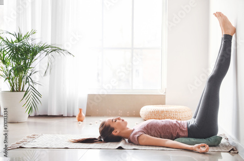 Fotografía Beautiful young woman practicing yoga at home
