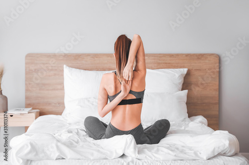 Cuadros en Lienzo Beautiful young woman practicing yoga in bedroom