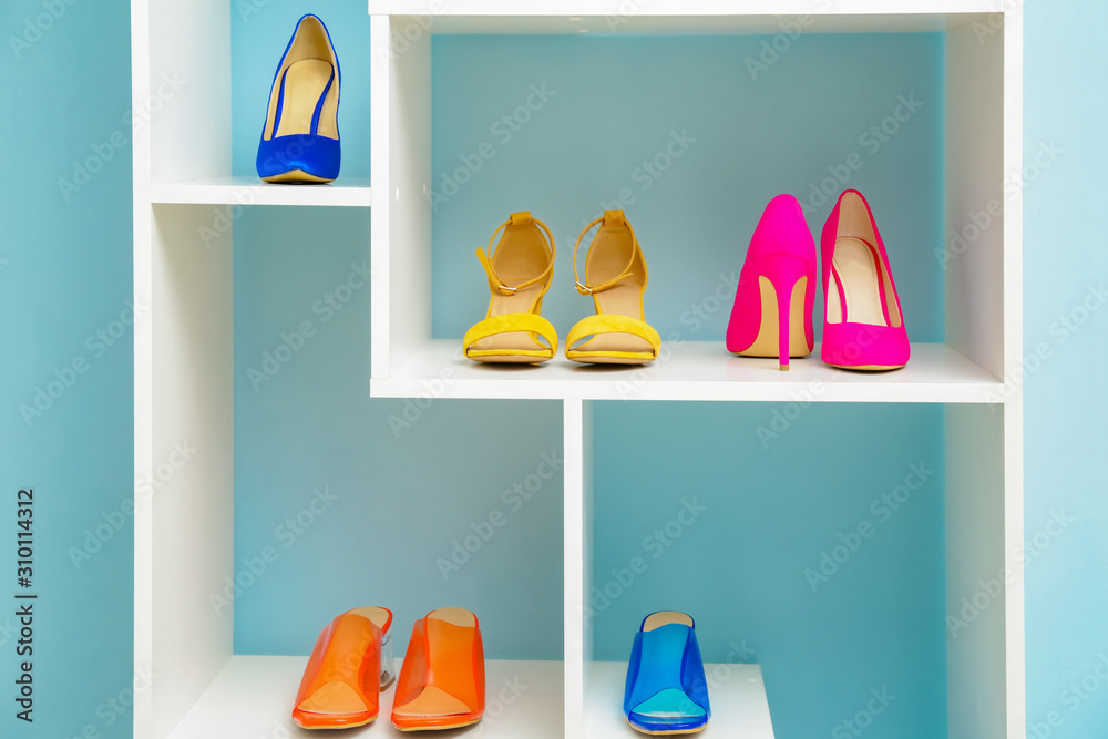 Shelf unit with stylish shoes near color wall