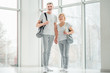 © HBS - Ready for sports lessons.Senior couple standing in the white spacious gym with sports equipment and holding hands and smiling at the camera. Health and sport concept. Comfortable sporty clothing.