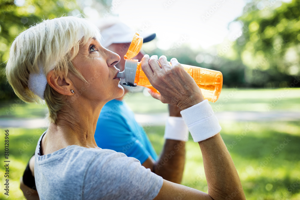 Mature couple drinks water to replenish energy and to hydrate - obrazy, fototapety, plakaty 