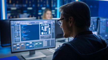 Wall Mural - Smart Male IT Programer Working on Desktop Computer in Data Center Technical System Control Room. Team of Young Professionals Programming in Coding Language