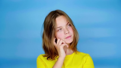teen girl in a yellow t-shirt is looking around at the place for text and thinks what to choose. blu