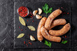 The concept of farm, organic products. Raw homemade pork barbecue sausages on a black slate board. background image. copy space