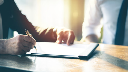 Closeup Businessman signing a contract investment professional document agreement on the table with pen.	