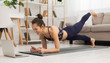 © Prostock-studio - Fit woman doing yoga plank and watching online tutorials on laptop