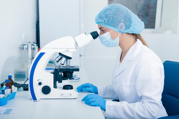 Poster - Young female Medical worker looking in microscope