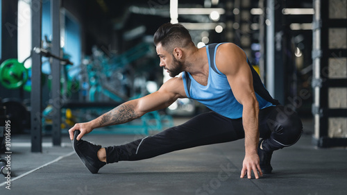 Fotografía Young athlete stretching legs before training at gym