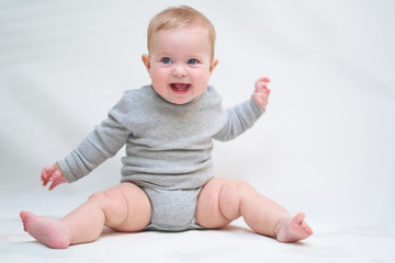 Wall Mural -  A 6 month old baby learns to sit down. photo on a neutral background