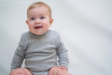 Wall Mural -  A 6 month old baby learns to sit down. photo on a neutral background