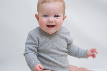 Wall Mural -  A 6 month old baby learns to sit down. photo on a neutral background