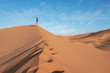 Young girl walking through the dunes in sahara desert in Morocco