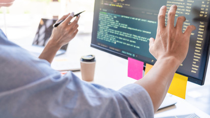 young startup programmers sitting at desks working on computers screen for developing programming an