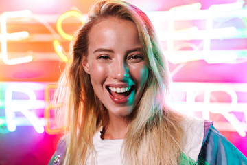 Poster - Image closeup of blonde woman smiling over multicolored neon text sign