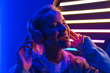 Sticker - Image of woman listening to music with headphones over neon illumination