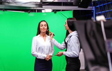 Presenter, makeup artist and video camera operator working in studio. News broadcasting