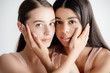 © LIGHTFIELD STUDIOS - young multicultural girls in beige outfit tenderly touching each other isolated on white