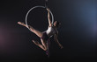 © New Africa - Young woman performing acrobatic element on aerial ring indoors