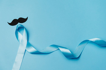 Top view on Light blue ribbon with mustache on blue background. Prostate Cancer Awareness, Movember Men's health awareness, November Blue, International Men's Day