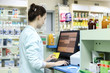 Female pharmacist works in a pharmacy. Pharmacist at the computer in the pharmacy.	