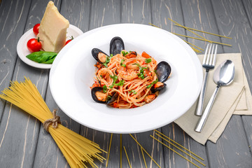 Wall Mural - pasta with shrimp and mussels, tomato sauce, basil and grated parmesan cheese