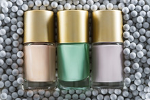 Top View Of Assorted Nail Polish In Bottles In Grey Decorative Beads