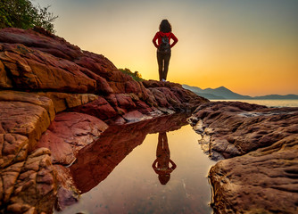 A woman standing at the beach in sunset