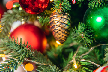 Multi-colored balls, sweets, lollipops, cones, toy decorate Christmas tree, background blurred for text