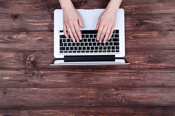 Poster - Female hands typing on laptop keyboard on wooden table