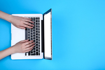 Poster - Female hands typing on laptop keyboard on blue background
