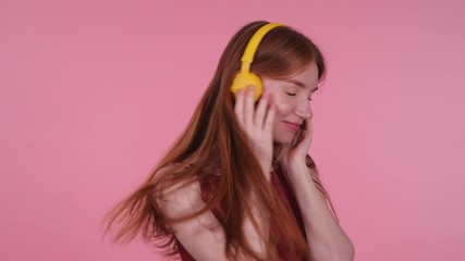 Poster - Beautiful young woman listening to music on pink background. Slow motion effect