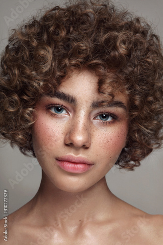 Fotografía Portrait of young beautiful freckled girl with curly hair and clean makeup