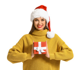 Beautiful young woman in Santa hat and with Christmas gift on white background