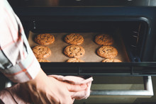 Woman Taking Baking Tray With Cookies Out Of Oven