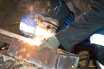 Man welder cooks metal. Sparks from the welding machine..