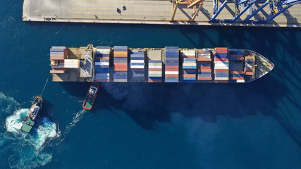 Aerial drone top down photo of industrial cargo container tanker ship carrier docked in commercial port terminal