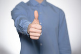 Fototapeta  - Close up of beautiful young man in a blue shirt  showing  like on white background. Hand like.  Gesturing hands stock image 