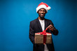 Young black businessman happy expression holding christmas gift isolated on blue background