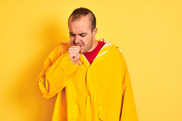 Sticker - Young man wearing rain coat standing over isolated yellow background feeling unwell and coughing as symptom for cold or bronchitis. Healthcare concept.