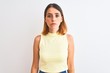 © Krakenimages.com - Beautiful redhead woman wearing yellow summer t-shirt over isolated background with serious expression on face. Simple and natural looking at the camera.