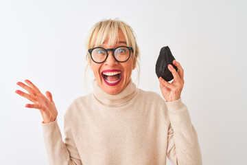 Sticker - Middle age woman wearing glasses holding avocado over isolated white background very happy and excited, winner expression celebrating victory screaming with big smile and raised hands