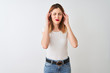 © Krakenimages.com - Beautiful redhead woman wearing casual t-shirt standing over isolated white background with hand on head for pain in head because stress. Suffering migraine.