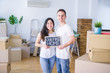 © Krakenimages.com - Young beautiful couple standing on the floor holding blackboard with message at new home around cardboard boxes