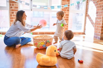 Poster - Beautiful teacher and toddlers playing around lots of toys at kindergarten