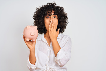 Sticker - Young arab woman with curly hair holding piggy bank over isolated white background cover mouth with hand shocked with shame for mistake, expression of fear, scared in silence, secret concept