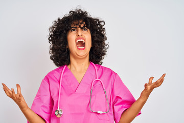 Sticker - Young arab doctor woman with curly hair wearing stethoscope over isolated white background crazy and mad shouting and yelling with aggressive expression and arms raised. Frustration concept.